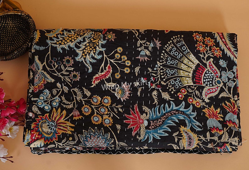 May include: Black kantha quilt with a floral pattern in shades of red, blue, yellow, and gold. The quilt is made of cotton and has a hand-stitched design.