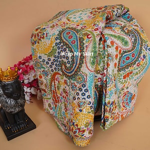 Pode incluir: Têxtil com padrão paisley multicolorido sobre fundo branco, com tons vibrantes de azul, verde, amarelo e laranja. O texto "Wrap My Skirt" é visível no tecido. O têxtil está dobrado, mostrando seu design.