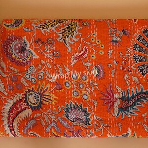 May include: Orange kantha quilt with a floral pattern. The quilt is made of cotton and has a hand-stitched design.