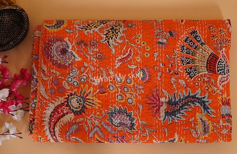 May include: Orange kantha quilt with a floral pattern. The quilt is made of cotton and has a hand-stitched design.