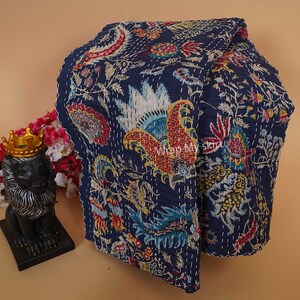 May include: A navy blue kantha quilt with a floral pattern in shades of red, yellow, green, and white. The quilt is hand-stitched and has a fringed edge.