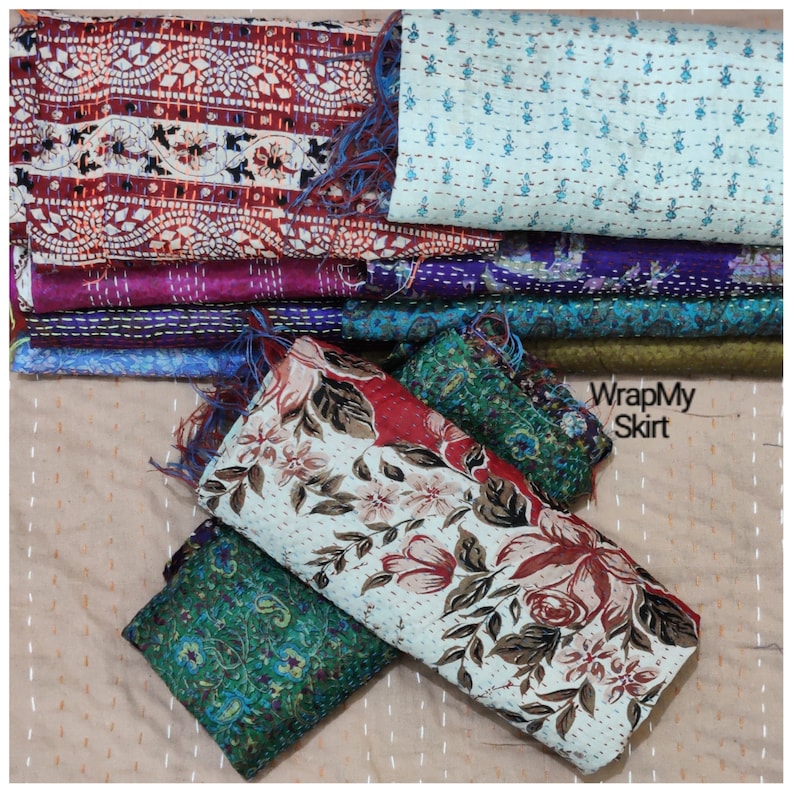 May include: A stack of colorful kantha quilts with floral and geometric patterns. The quilts are made from recycled saris and are perfect for adding a touch of bohemian style to your home.