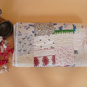 May include: A white patchwork quilt featuring a variety of floral and geometric patterns in shades of blue, red, green, and pink. The quilt is crafted from different fabrics stitched together to create a distinctive and textured design.