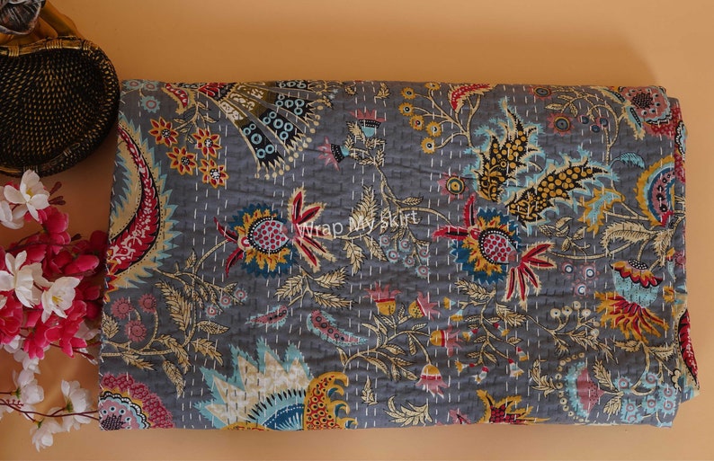 May include: A gray kantha quilt with a floral pattern in shades of red, yellow, blue, and green. The quilt is hand-stitched and has a traditional Indian design.