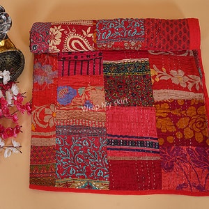 May include: A red and gold patchwork quilt with a variety of floral and paisley patterns. The quilt is made of kantha stitching and is a traditional Indian craft.