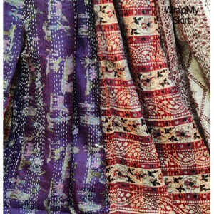 May include: A multi-colored kantha quilt with a purple, red, and white pattern. The quilt is made of cotton and has a hand-stitched design. The quilt is a traditional Indian textile.