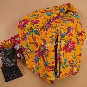 Könnte beinhalten: Eine gelbe Kantha-Steppdecke mit floralem und Vogelmuster. Die Decke ist gefaltet und trägt ein Etikett mit der Aufschrift "Wrap My Skirt".