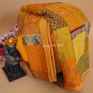 Puede incluir: Una colcha kantha amarilla y dorada hecha de saris reciclados. La colcha est&aacute; compuesta por muchos cuadrados de tela diferentes, cada uno con un patr&oacute;n diferente. La colcha est&aacute; cosida a mano y tiene un aspecto r&uacute;stico y hermoso.