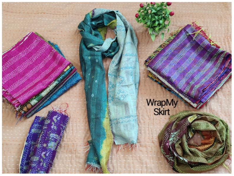 May include: Assortment of colorful kantha stitch scarves in various patterns and colors, including teal, blue, purple, pink, and green. The scarves are made of recycled saris and are perfect for adding a touch of bohemian style to any outfit.  WrapMySkirt.