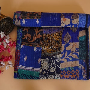 May include: A patchwork quilt with a blue background and various floral and geometric patterns in shades of brown, gold, green, and white. The quilt is made of recycled saris and is hand-stitched.