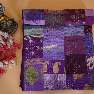 May include: Purple kantha quilt with a patchwork design. The quilt is made of various fabrics with different patterns and textures. The quilt is hand-stitched and has a unique, rustic look.