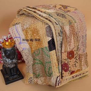 May include: A patchwork quilt in beige, brown, and floral patterns, with visible stitching. The quilt features the text "Wrap My Skirt". A decorative lion statue with a gold crown is in the background.