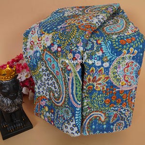 Könnte beinhalten: Eine gefaltete blaue Paisley-Steppdecke mit komplizierten Blumen- und Tropfenmustern in Orange-, Gelb-, Grün- und Weißtönen. Die Steppdecke besteht aus weichem Stoff und weist detaillierte Nähte auf.