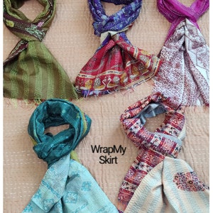 May include: Five colourful silk scarves with different patterns and colours. The scarves are folded and arranged on a light brown background. The text "WrapMy Skirt" is visible in the centre of the image.