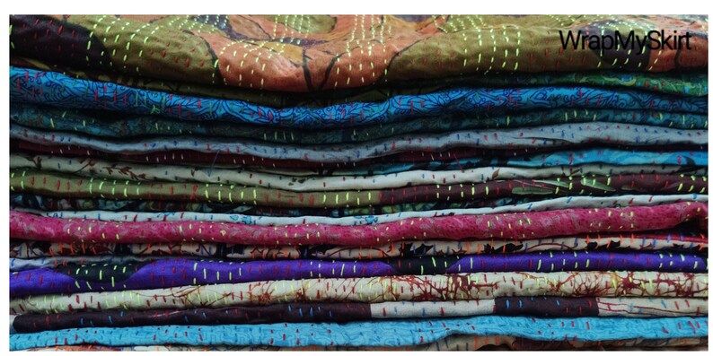 May include: A stack of colorful fabric squares with intricate stitching, likely for a quilt or patchwork project. The fabric is a mix of patterns and colors, including blue, green, red, and purple.