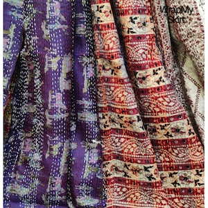 May include: A multi-colored kantha quilt with a purple, red, and white pattern. The quilt is made of cotton and has a hand-stitched design. The quilt is a traditional Indian textile.