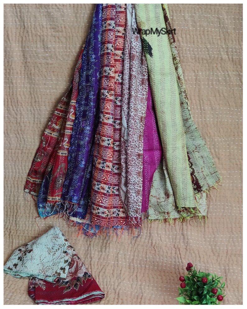 May include: A stack of colorful kantha quilts with a variety of patterns and textures. The quilts are made of recycled saris and are perfect for adding a touch of bohemian style to any home.