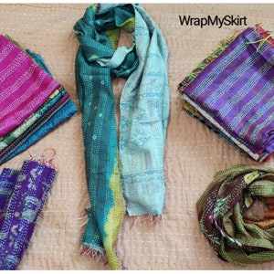 May include: Assortment of colourful kantha stitch scarves in various patterns and colours, including teal, purple, pink, and brown. The scarves are made of recycled silk and are perfect for adding a touch of bohemian style to any outfit. WrapMySkirt is a brand name.