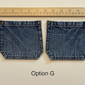 Pode incluir: Dois bolsos de ganga azul com rebites de metal e costuras decorativas. Uma r&eacute;gua &eacute; colocada acima dos bolsos. O texto "Option G" est&aacute; abaixo.