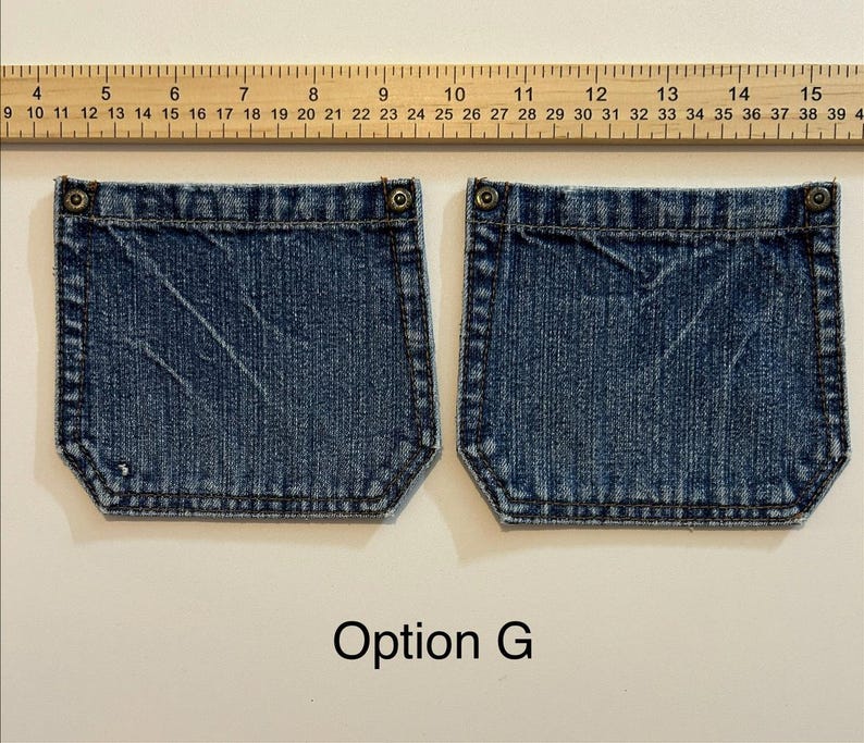 Pode incluir: Dois bolsos de ganga azul com rebites de metal e costuras decorativas. Uma r&eacute;gua &eacute; colocada acima dos bolsos. O texto "Option G" est&aacute; abaixo.