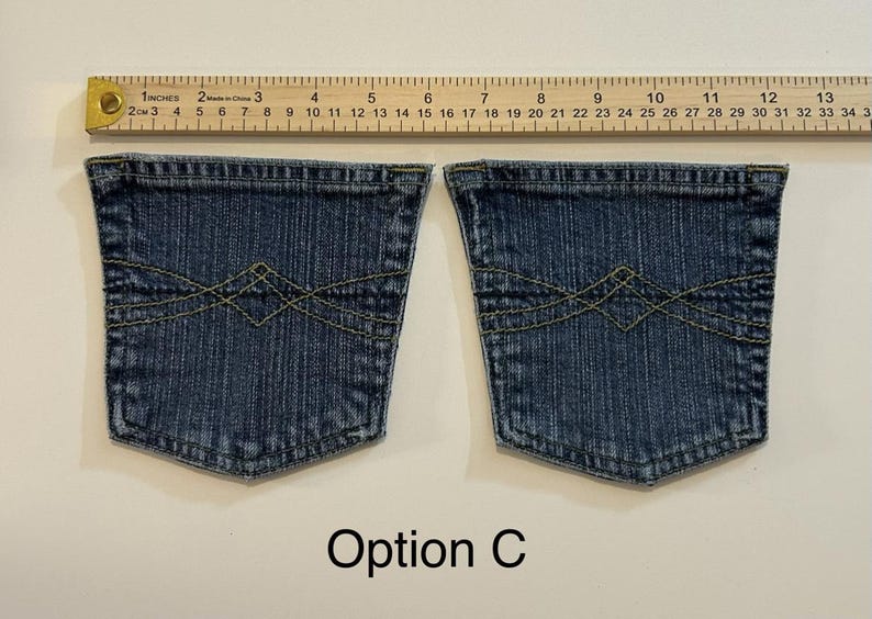 Pode incluir: Dois bolsos de cal&ccedil;as de ganga azuis com costuras amarelas e um design decorativo. Uma r&eacute;gua de madeira com medidas em polegadas est&aacute; acima dos bolsos. O texto "Op&ccedil;&atilde;o C" est&aacute; abaixo.