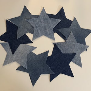 May include: A collection of eight denim blue star-shaped fabric pieces arranged in a circle.