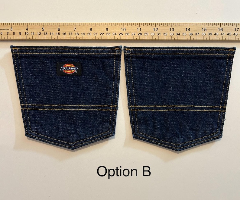 Pode incluir: Dois bolsos de ganga azul escuro com costuras amarelas. O bolso esquerdo tem um pequeno patch com o log&oacute;tipo Dickies. Os bolsos s&atilde;o mostrados ao lado de uma r&eacute;gua. O texto "Op&ccedil;&atilde;o B" est&aacute; na parte inferior.