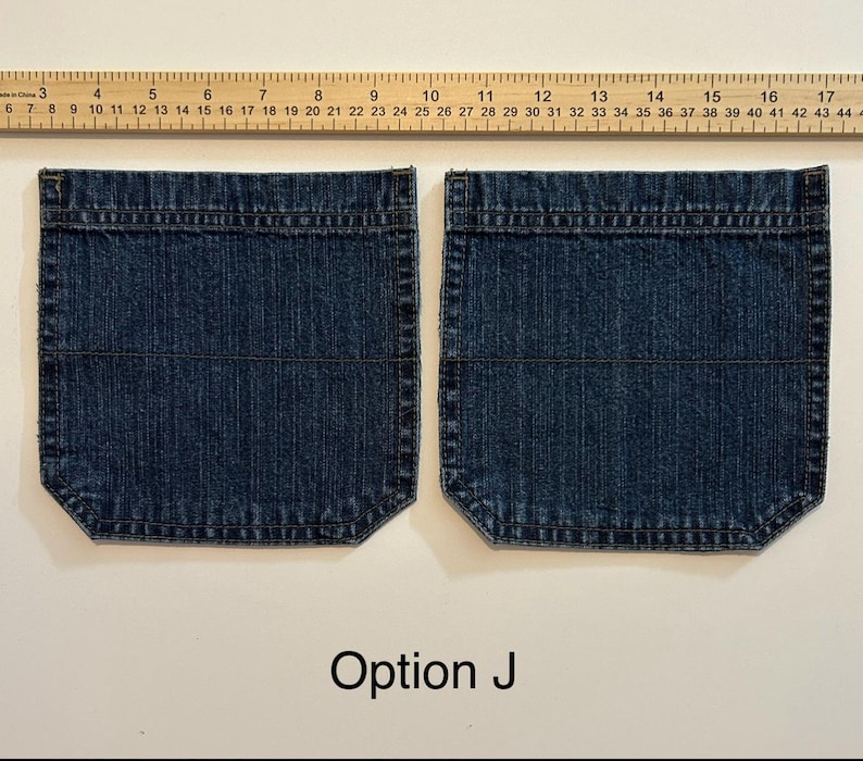 Pode incluir: Dois bolsos de ganga azul escuro com uma r&eacute;gua por cima. Os bolsos s&atilde;o retangulares com cantos arredondados e costuras horizontais. O texto "Op&ccedil;&atilde;o J" est&aacute; na parte inferior.