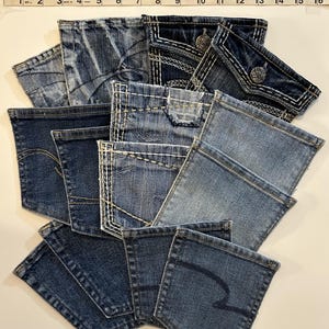 May include: A collection of ten denim jean pockets in various shades of blue. The pockets are arranged in a layered, overlapping pattern.