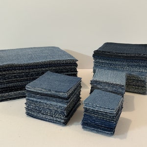 May include: A stack of denim fabric squares in various shades of blue, ranging from light to dark. The squares are arranged in different sizes and heights, creating a visually appealing display.