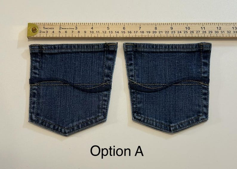 Pode incluir: Dois bolsos de ganga com uma r&eacute;gua medindo 33 cm. Os bolsos s&atilde;o azuis escuros com uma costura superior curva e formato retangular. O texto "Op&ccedil;&atilde;o A" est&aacute; abaixo dos bolsos.