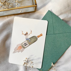 May include: A watercolor illustration of a woman wearing a crown and riding a champagne bottle shaped like a rocket with the number 40 on it. The woman is holding a glass of champagne in each hand.