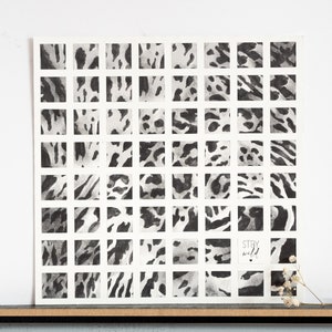 May include: A square art print featuring a grid of 48 black and white animal print patterns. The phrase "Stay Wild" is written in a small, handwritten font. The artwork is displayed on a white background.