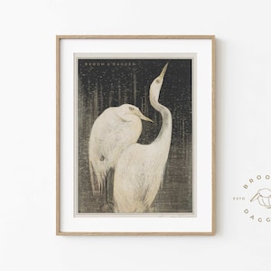 May include: A framed print of two white egrets standing in a dark, textured background. The print is titled "Broom & Dagger" and features a stylized illustration of the birds.