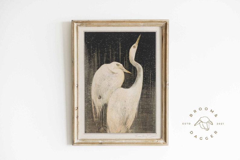 May include: A framed print of two white egrets standing in a dark, textured background. The egrets are facing each other, with their necks curved and their heads tilted. The print is in a light wood frame.