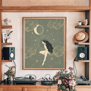 May include: A wood table with a vase of flowers on it. The table is in front of a bookshelf and a wall with a framed print of a woman standing on a cloud with a crescent moon and stars behind her.
