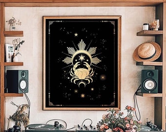 May include: A gold and black framed print of a zodiac sign with a crab design. The print is hanging on a wall with a wooden bookshelf and a wooden table in the foreground.