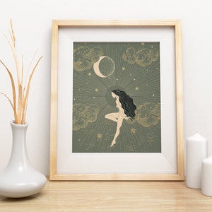 May include: A framed print with a green background featuring a woman with long black hair sitting on a cloud with a crescent moon and stars in the background.