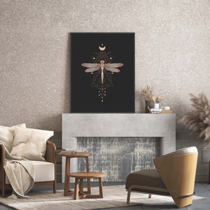 May include: A black and gold framed print with a geometric design featuring a dragonfly in the center. The dragonfly is brown and has a gold outline. The print is hanging above a fireplace.