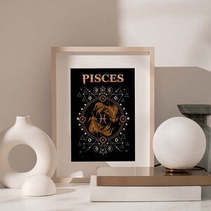Puede incluir: Una impresi&oacute;n en negro y dorado con la palabra "Pisces" en una fuente estilizada. La impresi&oacute;n presenta dos peces estilizados dentro de un c&iacute;rculo de formas y s&iacute;mbolos geom&eacute;tricos.