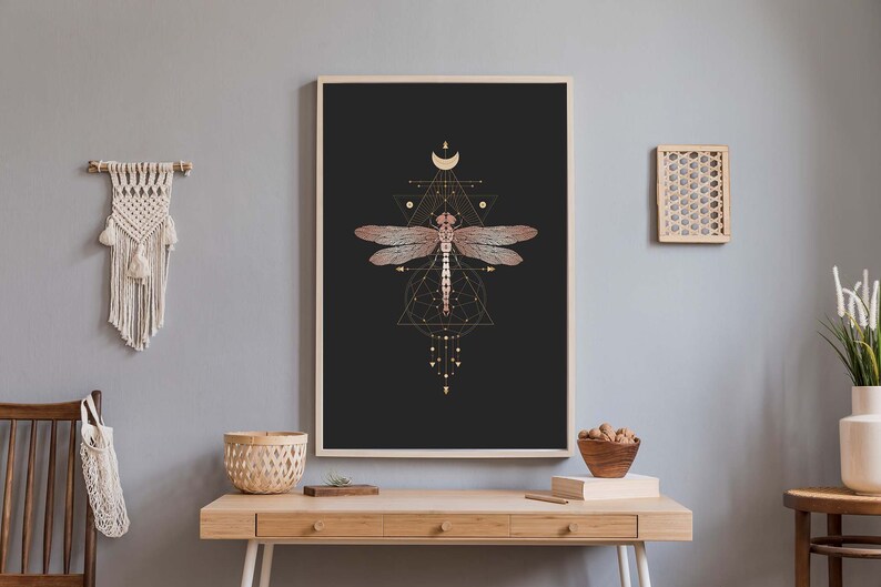 May include: A black and gold geometric print featuring a dragonfly with a crescent moon and stars. The dragonfly is pink and gold with a black outline.