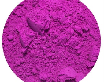 Puede incluir: Primer plano de un vibrante polvo magenta, que llena un marco circular. El polvo tiene una apariencia fina y texturizada con grumos visibles, lo que sugiere un pigmento o producto cosmético. El color brillante domina la imagen.