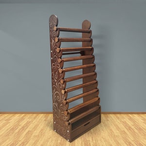 May include: A wooden yarn holder with a decorative floral design. It has 10 round dowels for storing yarn and a drawer at the bottom.