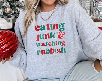 May include: A gray sweatshirt with the text "eating junk & watching rubbish" in red and green letters.