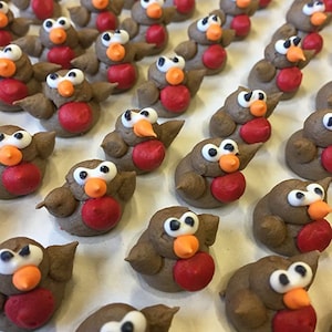 Könnte beinhalten: Eine Sammlung von braunen und roten Robin-Vogel-Kuchendekorationen. Die Rotkehlchen haben weiße Augen, orangefarbene Schnäbel und rote Bäuche.