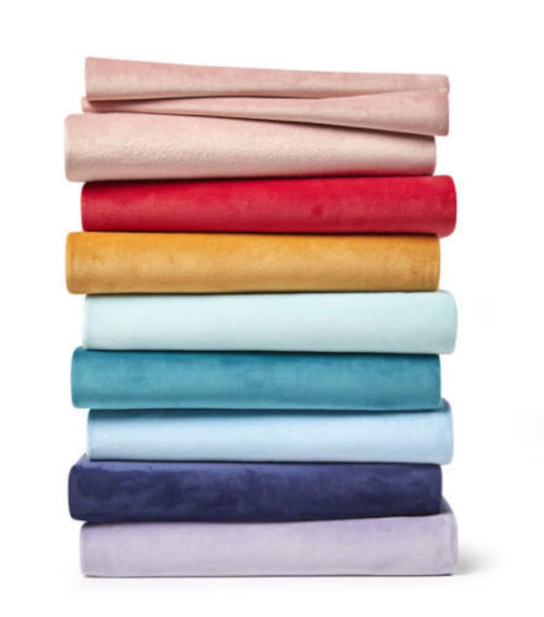 May include: A stack of ten fabric swatches in various colors, including pink, red, yellow, light blue, teal, blue, and purple. The swatches are folded and stacked on top of each other.