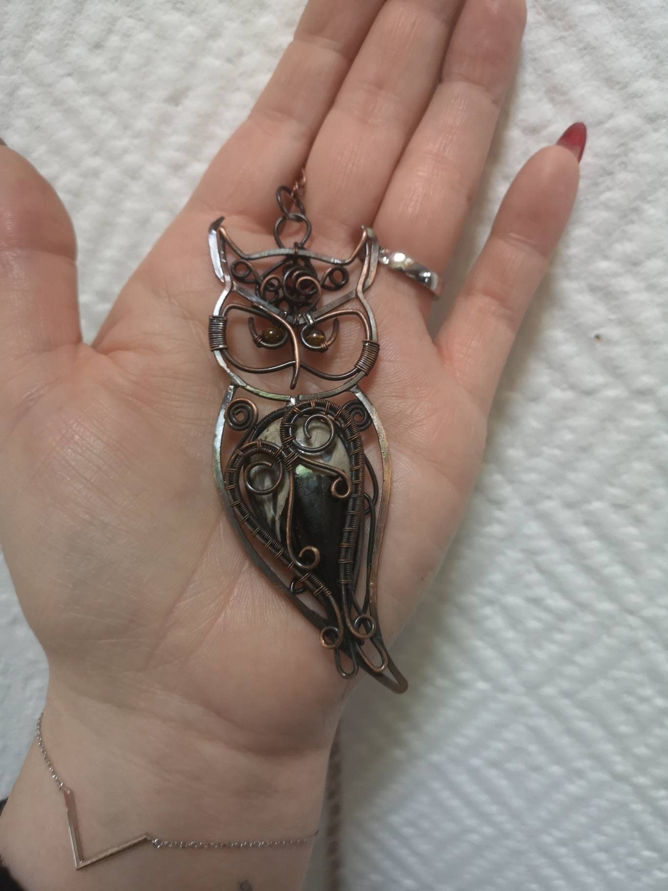 Le collier pendentif hibou des forêts réalise avec une racine de palmier focille .