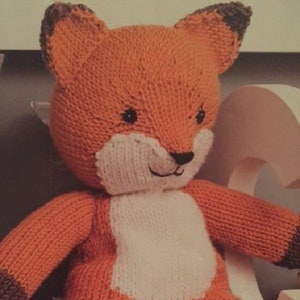 Peut inclure: Un jouet en peluche de renard orange tricoté avec des accents blancs sur le ventre, la queue et le visage. Le renard a des oreilles brunes et un nez noir.