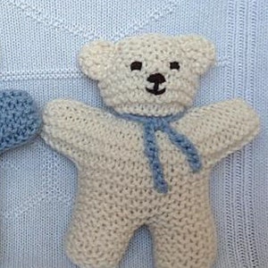 May include: Two knitted teddy bears, one blue and one white, with embroidered faces. The blue bear has a blue scarf and the white bear has a blue scarf.
