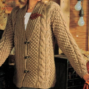 May include: A brown knitted cardigan with a cable knit pattern and a button closure. The cardigan has a leaf-shaped pin on the front.